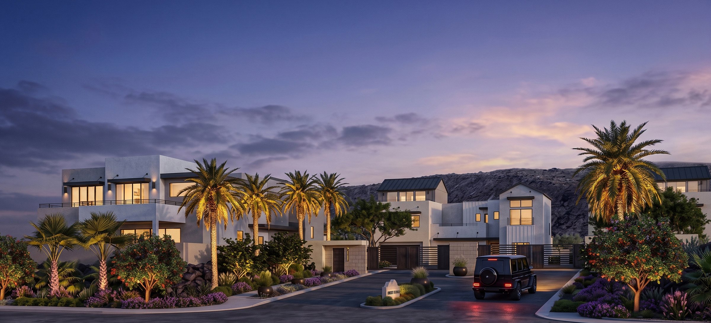 The gated entry at Rocky Ridge at twilight, with the community monument sign, lit palms and the ridgeline behind the homes.